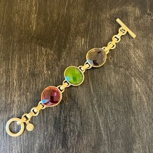 AK statement bracelet in flat gold tone.